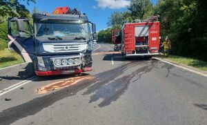 uszkodzony samochód ciężarowy na drodze, w tle straż pożarna