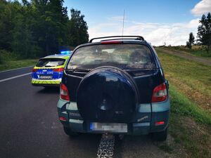 na drodze zatrzymany po pościgu samochód, przed nim radiowóz