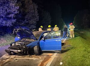uszkodzony samochód na drodze, w tle strażacy