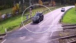 Auto osobowe o które opiera się szlaban przed przejazdem kolejowym.