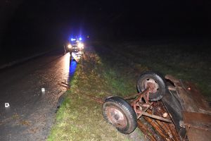 wóz z drewnem leży na poboczu w tle na ulicy radiowóz