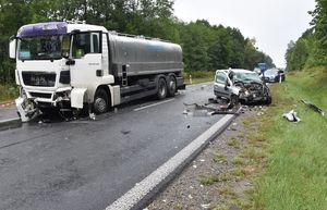 pojazd ciężarowy stoi na drodze, obok niego roztrzaskany samochód osobowy